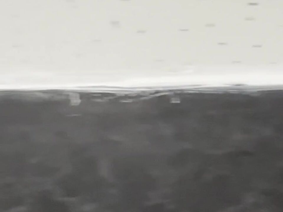 Thin threads of white sealant lying on the black worktop below the wall joint